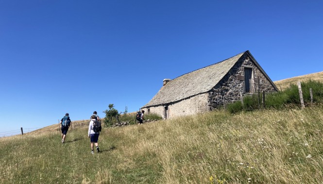 Groupe de randonneurs près d'un buron en Aubrac