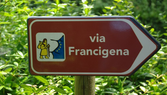 Panneau de signalisation marron de la Via Francigena avec le logo du pèlerin et le symbole européen, fléchant la direction du ch