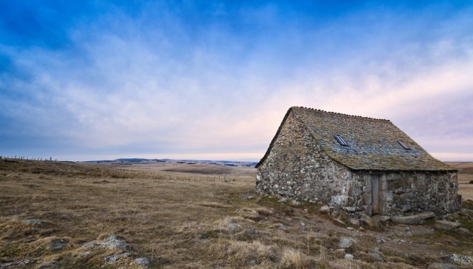 Buron traditionnel en pierre sur le plateau de l'Aubrac, Lozère, Occitanie, paysages d'altitude sous ciel bleu