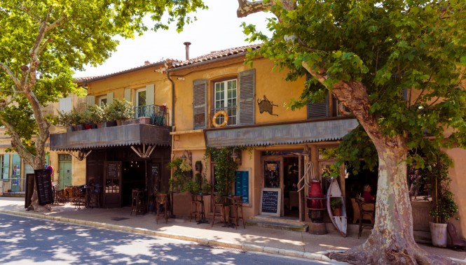 Façade d'un restaurant provençal à Maussane-les-Alpilles, avec terrasse ombragée sous les platanes