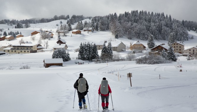Randonneurs en raquette dans un village enneigé du Jura