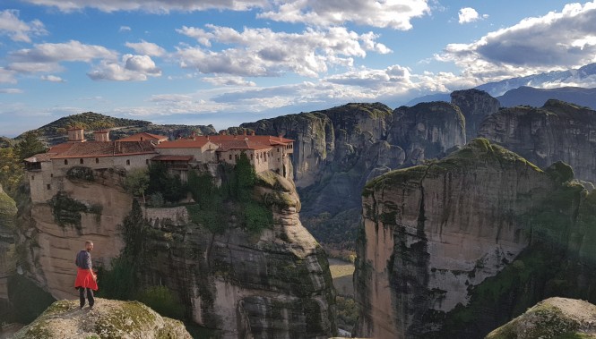 Monastère orthodoxe perché sur les falaises des Météores en Grèce, vue panoramique avec un randonneur.